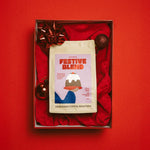 Festive Blend coffee package in a decorative box with red ribbon and ornaments on a red background